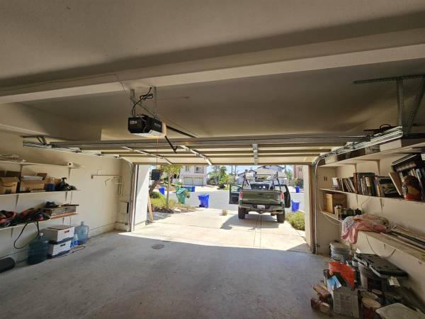 Repairing a residential garage door in Bell Gardens, California with the hardware and track exposed